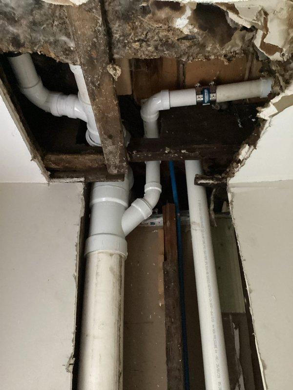 Completed full drain stack replacement from second floor through to basement. Opened walls and ceilings to access deteriorated plumbing infrastructure showing significant water damage and structural staining. Removed old drain stack and installed new PVC piping system, reconnecting all fixture drain lines including four toilet lines, four sink lines, and two tub lines. All connections properly fitted with appropriate elbows, joints, and couplings to ensure proper drainage flow throughout the vertical stack system.