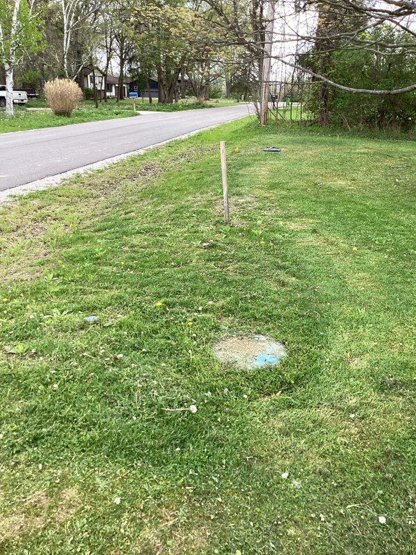 Conducted on-site estimate for new construction plumbing connection where municipal sewer line has been installed and requires hookup to residence with existing septic system removal. Assessed property conditions, located existing septic tank access points and new sewer connection point marked in lawn, and documented site conditions through photographic documentation to develop scope of work for transitioning from septic to municipal sewer service.