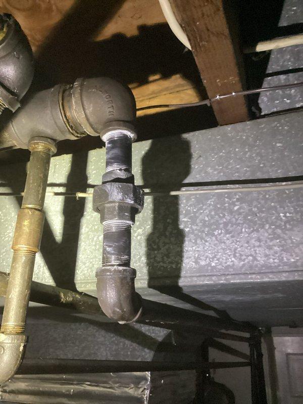 # Plumbing Service Completed

Responded to service call for suspected gas leak originating from HVAC system in residential property constructed in 1964. Upon arrival, conducted thorough inspection of mechanical systems in basement/crawl space area and accessed plumbing behind interior wall. 

Inspection revealed aging brass and copper piping with threaded connections showing signs of corrosion and surface discoloration consistent with original 1964 installation. Examined valve assembly with brass fittings and multiple pipe segments with threaded couplings supported by foam pipe insulation. Created wall access point to expose concealed plumbing system for comprehensive evaluation of pipe conditions and connections.

Assessed horizontal pipe runs with valves and connectors for potential leak sources. Evaluated condition of all visible joints, fittings, and connections throughout the plumbing system. Inspected interface between plumbing components and HVAC ductwork to identify potential g