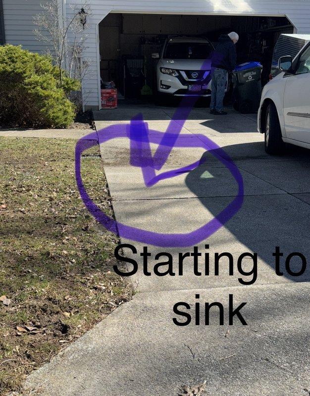 Responded to service call regarding ground water drain concerns and driveway subsidence. Inspected utility access vault with latticed metal grate, documenting existing drainage infrastructure including visible piping, valve assemblies, and connection components within the recessed cavity. Assessed driveway conditions where concrete sections showed signs of settlement and sinking, marking affected areas for reference. Examined grate stability issues where current cover design allows displacement during water flow events. Recommended drain line inspection for potential blockages and evaluation of underground drainage system integrity to determine if compromised piping is contributing to driveway settlement. Advised consideration of alternative grate design with secured mounting to prevent flotation during high water flow conditions.