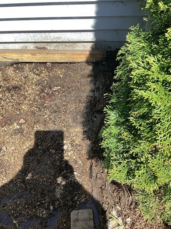 Responded to water leak investigation at a 70-year-old residential property where the homeowner suspected a leak originating from the well system. Conducted thorough inspection of exterior grounds near the foundation, identifying dark staining and moisture accumulation on concrete surfaces adjacent to the structure. Inspected interior plumbing infrastructure in the basement utility area, examining vertical pipe runs, PVC supply lines, and connections near the water heater to rule out interior sources. Documented findings with photographic evidence of both exterior ground conditions and interior plumbing configuration for further evaluation and repair recommendations.