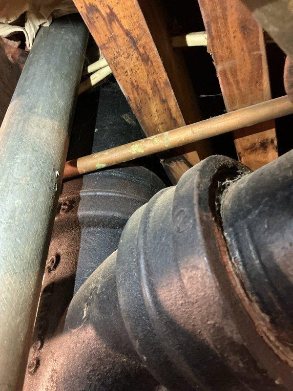 Responded to a plumbing service call for a basement pipe leak and exterior drainage concern in a residential property constructed circa 1970. Upon arrival, inspected the basement plumbing system and identified a corroded metal pipe component showing significant rust deterioration with visible brown and orange oxidation throughout the affected section. The corrosion patterns indicated prolonged exposure to moisture and age-related material degradation consistent with original 1970s-era plumbing infrastructure.

Conducted a thorough assessment of the basement leak source, examining pipe connections, joints, and surrounding structural components including wooden support beams and framing materials in the overhead space. Documented the extent of corrosion on the affected metal piping and evaluated the integrity of adjacent plumbing lines to determine if additional sections required attention or replacement.

Proceeded to the exterior of the property to investigate the reported drainage iss