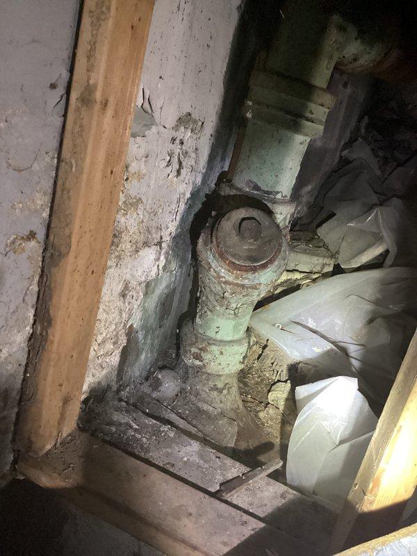 Responded to main drain backup in basement utility area. Upon arrival, contacted tenant prior to service as requested. Inspected main drain cleanout located in deteriorated basement corner with aging infrastructure. Cleanout access point identified on vertical PVC drain line showing signs of long-term use and environmental wear. Cleared main drain obstruction using appropriate drain cleaning equipment. Verified proper drainage flow restored through system. Documented existing conditions of surrounding plumbing infrastructure including corroded pipes and aged building materials for service records.