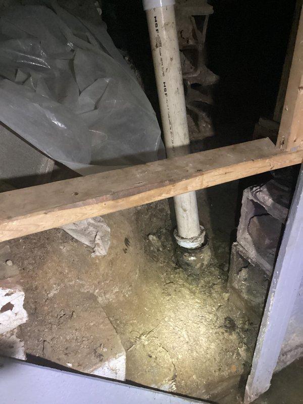 Responded to main drain backup in basement utility area. Upon arrival, contacted tenant prior to service as requested. Inspected main drain cleanout located in deteriorated basement corner with aging infrastructure. Cleanout access point identified on vertical PVC drain line showing signs of long-term use and environmental wear. Cleared main drain obstruction using appropriate drain cleaning equipment. Verified proper drainage flow restored through system. Documented existing conditions of surrounding plumbing infrastructure including corroded pipes and aged building materials for service records.