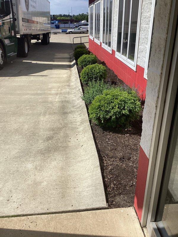 Conducted complimentary site assessment for commercial property experiencing water drainage issues along building perimeter. Evaluated existing landscape and grading conditions, documenting areas where surface water accumulates near foundation. Photographed current site conditions including building exterior, sidewalk areas, and landscaped zones to develop French drain installation proposal that will redirect groundwater away from structure.