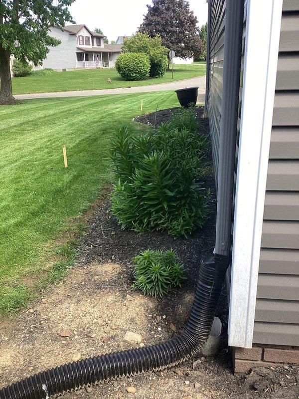 Performed camera inspection of exterior drainage system at 36-year-old residential property. Inspected downspout drainage lines and underground corrugated pipe routing from house foundation through landscaped areas. Documented drainage pipe condition, flow path, and termination points to assess system functionality and identify any potential blockages or structural concerns.