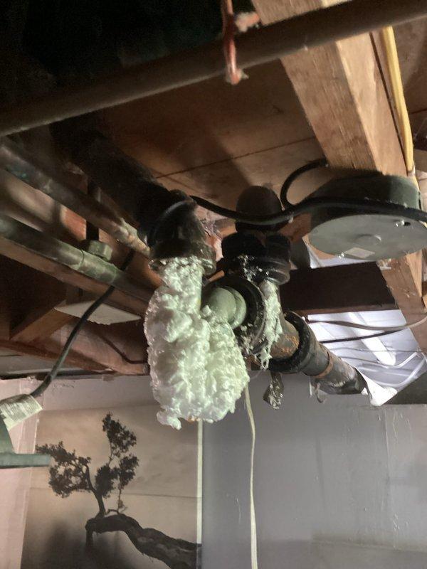 Responded to emergency call for basement flooding caused by main drain backup. Upon arrival, found significant standing water throughout basement storage area with muddy sediment covering entire floor surface. Accessed garage floor drain cleanout and performed large-capacity drain snaking procedure to clear main line obstruction. Successfully removed blockage and restored proper drainage flow. Verified system functionality and confirmed water began receding from affected area. Documented pre-existing flood damage to basement contents including furniture, storage containers, and various household items. Photographed flooded conditions and exposed basement infrastructure including plumbing lines, HVAC ductwork, and spray foam insulation applications on overhead systems.