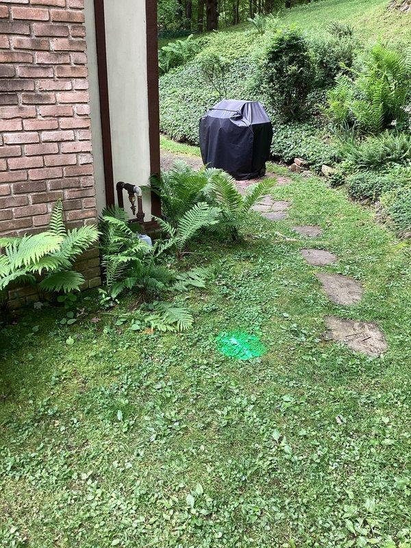 Responded to service call for assessment of ground water drainage system experiencing potential blockage in lawn area. Conducted comprehensive plumbing inspection of exterior drainage infrastructure, locating and marking underground drain lines with fluorescent green paint for identification. Evaluated drainage flow patterns across sloped residential property, examining multiple drain access points throughout backyard lawn area near stone pathway and fence line. Assessed condition of subsurface drainage system to determine extent of clog and recommend appropriate remedial action for restoring proper ground water flow. Documented site conditions with photographic evidence showing marked drain locations and property layout for estimate preparation.