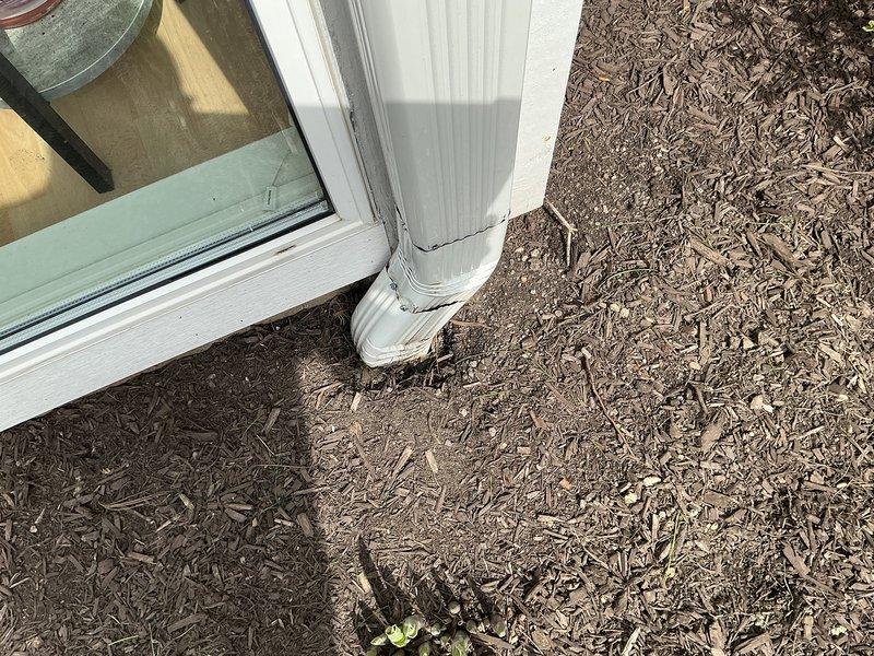 # Plumbing Service Completed

Responded to a recurring drainage issue with a rear downspout that had previously been jetted under work order XN2317096. Upon arrival, found the jetting equipment was non-operational, preventing use of the standard high-pressure water jetting method for clearing the underground drain line. Assessed the downspout discharge point at the building foundation where the vertical leader connects to the below-grade drainage system through a white elbow fitting. The area around the discharge point was landscaped with wood mulch ground cover adjacent to the building's white exterior siding. Documented current site conditions including the downspout configuration, connection points, and surrounding landscape features for follow-up service planning. Due to equipment unavailability, the blockage in the underground drain line remains unresolved and will require a return visit with operational jetting equipment to properly clear the obstruction and restore proper draina