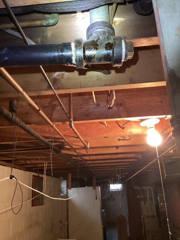 Performed main drain cleanout service in basement area as part of follow-up visit. Accessed main drain line through existing cleanout point, successfully cleared blockage and restored proper drainage flow. Inspection revealed significant corrosion present on metal pipe coupling components in the drain system, which was documented photographically for future maintenance planning.