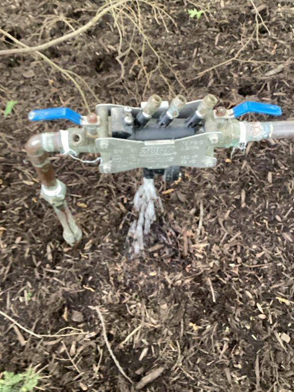 Responded to service call for cracked backflow prevention device on irrigation system. Upon arrival, inspected 1" Wilkins 375 backflow preventer (Serial# B152990) located in front left corner near street that had been previously shut off to prevent water leakage. Replaced damaged backflow assembly with new unit, reconnected white PVC supply lines and blue distribution piping to manifold assembly. Performed complete backflow test per industry standards to verify proper check valve operation and system integrity. Restored water supply to sprinkler system and confirmed no leaks at connections.