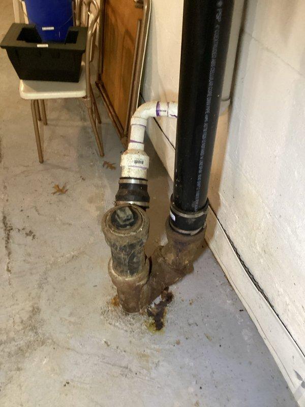 Responded to kitchen drain clog complaint and performed drain service to clear the blockage. Upon inspection of the basement plumbing system, identified significant corrosion and deterioration on the main sewer line where it enters through the concrete floor. The cast iron piping shows advanced rust damage with visible staining at the base connections, indicating active corrosion that will require main sewer line replacement in the near future to prevent system failure. Documented existing conditions with photographs for future reference and recommended scheduling sewer line replacement to avoid emergency situations.