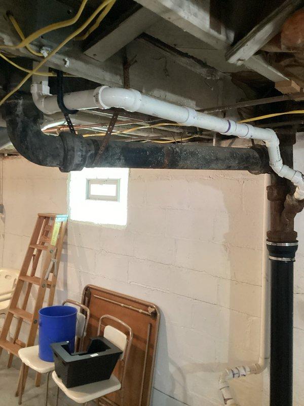 Responded to kitchen drain clog complaint and performed drain service to clear the blockage. Upon inspection of the basement plumbing system, identified significant corrosion and deterioration on the main sewer line where it enters through the concrete floor. The cast iron piping shows advanced rust damage with visible staining at the base connections, indicating active corrosion that will require main sewer line replacement in the near future to prevent system failure. Documented existing conditions with photographs for future reference and recommended scheduling sewer line replacement to avoid emergency situations.