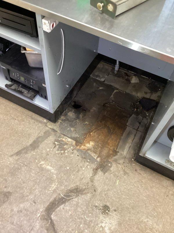 Performed camera inspection and jetting service on commercial kitchen drain line serving sandwich preparation station experiencing backup issues when sink was drained. Conducted video inspection to identify blockage location and condition of drain line, followed by hydro-jetting to clear obstruction and restore proper drainage flow. Documented equipment conditions and water damage present in affected areas, with visible moisture and staining observed on flooring surfaces near HVAC equipment and cabinet installations.