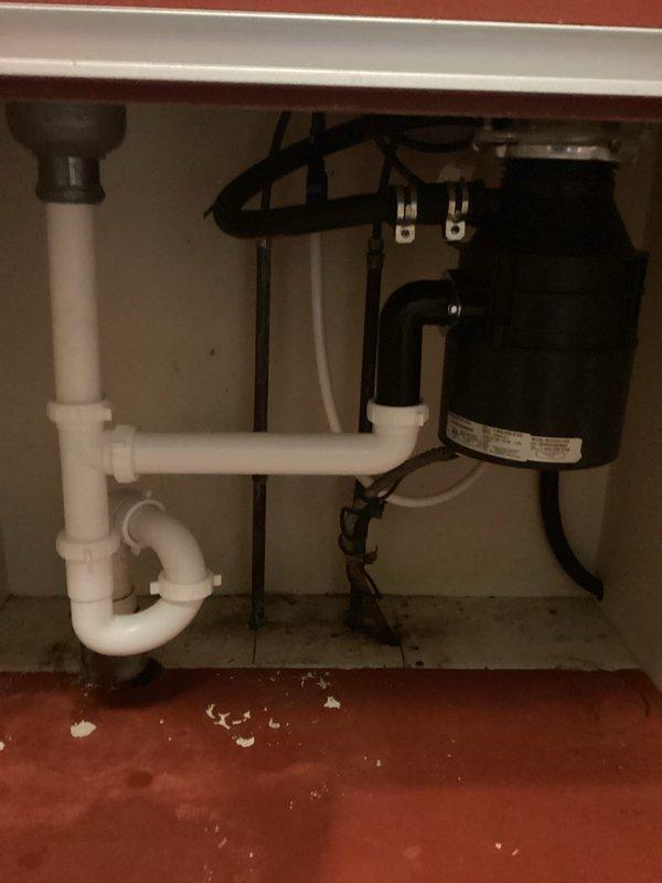 Completed repair service on kitchen sink plumbing system, including work on the drain assembly and garbage disposal unit beneath the double-basin stainless steel sink. Addressed plumbing issues with the P-trap configuration and associated drainage components to restore proper function to the sink system.