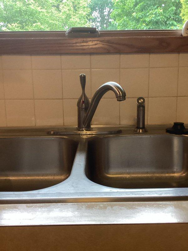 Completed repair service on kitchen sink plumbing system, including work on the drain assembly and garbage disposal unit beneath the double-basin stainless steel sink. Addressed plumbing issues with the P-trap configuration and associated drainage components to restore proper function to the sink system.