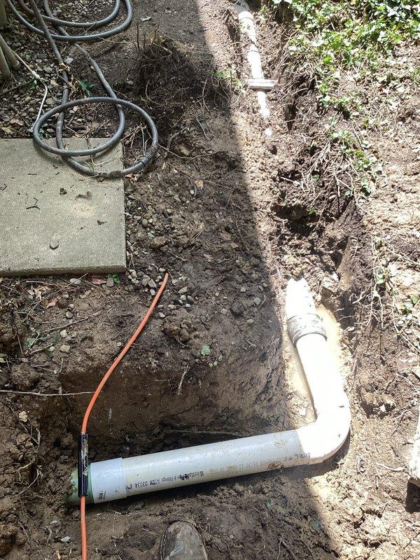 Excavated and exposed damaged section of underground drainage line beneath deck area. Removed approximately 5 feet of deteriorated pipe and replaced with Schedule 35 PVC piping, including proper fitting connections. Performed video camera inspection of downstream drainage system to verify pipe integrity and confirm no additional breaks or damage beyond repair area. Backfilled excavation upon completion of work.