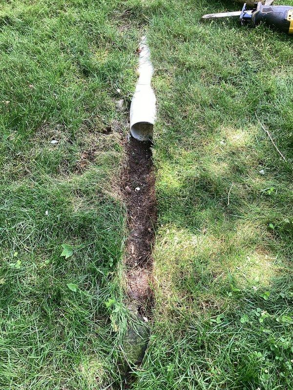 Responded to service call for damaged underground PVC drainage line that had been severed by lawn mower. The affected pipe was part of the downspout discharge system. Excavated trench to expose the damaged section of white PVC pipe, removed the compromised portions, and installed replacement piping to restore proper drainage function. Backfilled trench upon completion of repairs.