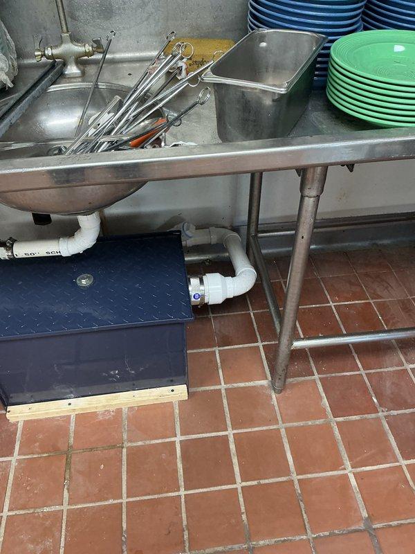 Completed commercial kitchen plumbing installation to support dishwasher and pre-rinse station operations. Repaired pipe within wall cavity and installed under-sink grease trap with proper permitting. Installation included PVC drain line configuration connecting to three-compartment sink system, copper supply line connections with shut-off valves, and integration with existing Scotts-Chill dishwasher equipment. All plumbing work performed to code specifications for commercial food service facility requirements.