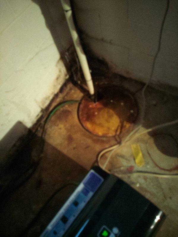 Provided free estimate for sump pump replacement in basement utility area. Assessed existing sump pump system, drainage infrastructure, and vertical discharge piping running from floor to ceiling, noting staining and water damage on concrete floor surrounding pump base. Customer considering coordinating sump pump replacement with previously estimated downspout work.