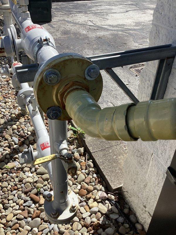 Responded to commercial gas line service call requiring flange replacement. Upon arrival, inspected existing outdoor gas line assembly mounted on building exterior and identified severely weathered and corroded brass flange connection showing significant oxidation and green patina buildup. The deteriorated flange posed potential safety concerns and required replacement with proper specification component. Assessed the complete gas line configuration including associated piping, valving, and support systems to ensure compatibility with replacement flange. Documented existing installation conditions through photographs showing the corroded flange connection, mounting hardware, and surrounding utility infrastructure. Provided proper flange component suitable for the natural gas application to restore safe and code-compliant operation of the commercial gas line system.