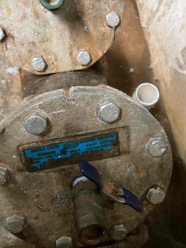 Responded to backflow system issue. Performed inspection of backflow preventer assembly, which showed significant age and corrosion on flanged components and connections. Evaluated condition of device including manufacturer markings and test ports. Documented equipment condition through photographs showing weathered metal surfaces, worn protective coating, and visible rust discoloration on flange bolts and assembly. Test cocks and valve mechanisms were assessed for functionality. System evaluation completed and findings recorded for customer review.