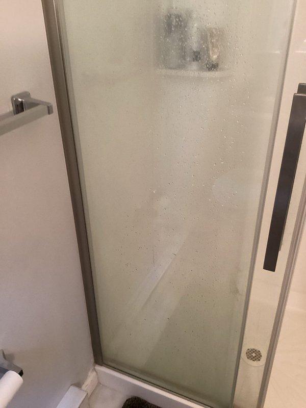 Responded to service call for cracked tub surround in rental property. Upon arrival, inspected fiberglass shower/tub enclosure and confirmed structural damage to the molded surround panels. The crack was located in the corner section where wall panels meet the tub basin. Additionally, noted mold or mildew buildup on the frosted glass shower door near the top center, approximately 3-4 inches in size, indicating moisture intrusion issues. Documented existing conditions with photographs for repair assessment and invoicing purposes. Provided recommendations for tub surround replacement to address the structural compromise and prevent further water damage to surrounding areas.