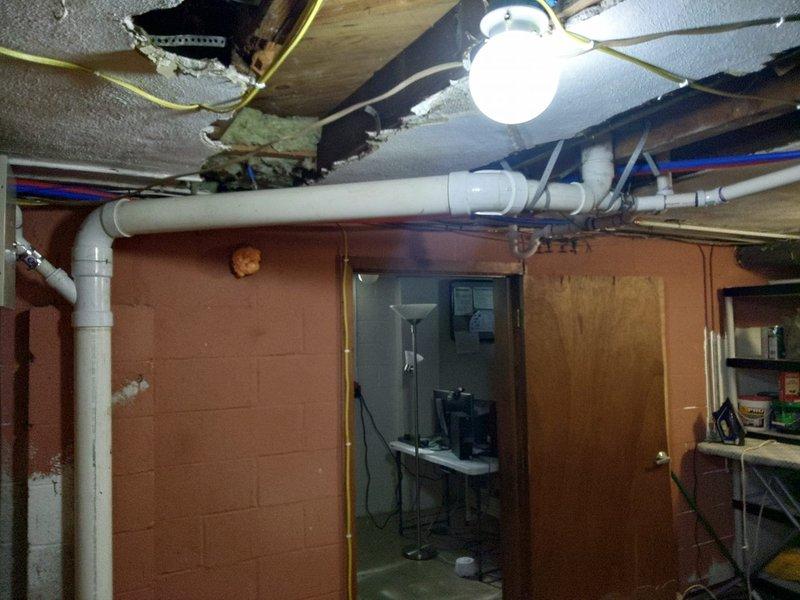 Responded to emergency plumbing call for damaged stack pipe replacement in basement utility area. Upon arrival, found extensive water damage to ceiling with compromised structural materials and exposed joists surrounding the failed plumbing stack. Removed deteriorated ceiling materials and damaged insulation to access the affected plumbing system. Replaced the vertical stack pipe with new white PVC piping, ensuring proper alignment and secure connections throughout the installation. Coordinated work with existing horizontal drain lines and vent pipes in the overhead system. Verified all joints were properly sealed and tested the new stack for leaks and proper drainage flow. Work completed as specified in approved proposal, restoring full functionality to the plumbing system and eliminating the source of water damage.
