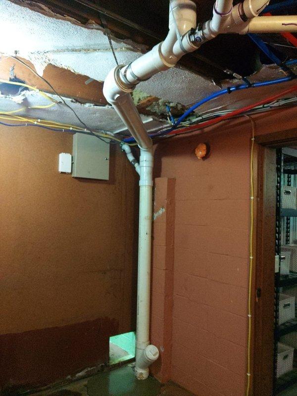 Responded to emergency plumbing call for damaged stack pipe replacement in basement utility area. Upon arrival, found extensive water damage to ceiling with compromised structural materials and exposed joists surrounding the failed plumbing stack. Removed deteriorated ceiling materials and damaged insulation to access the affected plumbing system. Replaced the vertical stack pipe with new white PVC piping, ensuring proper alignment and secure connections throughout the installation. Coordinated work with existing horizontal drain lines and vent pipes in the overhead system. Verified all joints were properly sealed and tested the new stack for leaks and proper drainage flow. Work completed as specified in approved proposal, restoring full functionality to the plumbing system and eliminating the source of water damage.