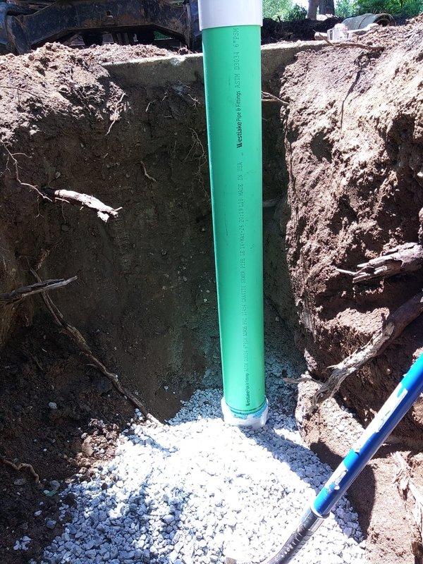 Excavated and exposed damaged sanitary sewer line, removed deteriorated section, and installed new green PVC sewer pipe with proper metallic coupling connections. Backfilled excavation with crushed stone bedding for drainage and stability, ensuring proper pipe support and grade for optimal wastewater flow.