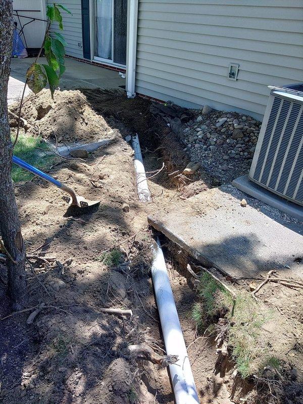 Completed downspout repair and drainage system restoration per approved proposal. Excavated and exposed existing PVC drainage line running from the building foundation, replaced damaged sections of downspout piping, and properly graded the area to ensure optimal water flow away from the structure. Backfilled excavation with appropriate materials, restored landscaping around HVAC condenser unit, and verified system functionality through water flow testing.