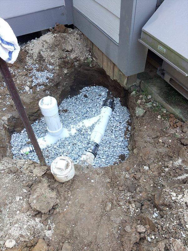 Completed main sewer line repair requiring excavation adjacent to building foundation. Exposed and replaced damaged sewer piping with new PVC pipe sections, installed within proper gravel bedding for drainage and structural support. Work included trenching, removal of failed pipe segments, installation of new connections with appropriate fittings, and backfilling with drainage rock to ensure long-term system integrity and proper water flow away from the foundation.
