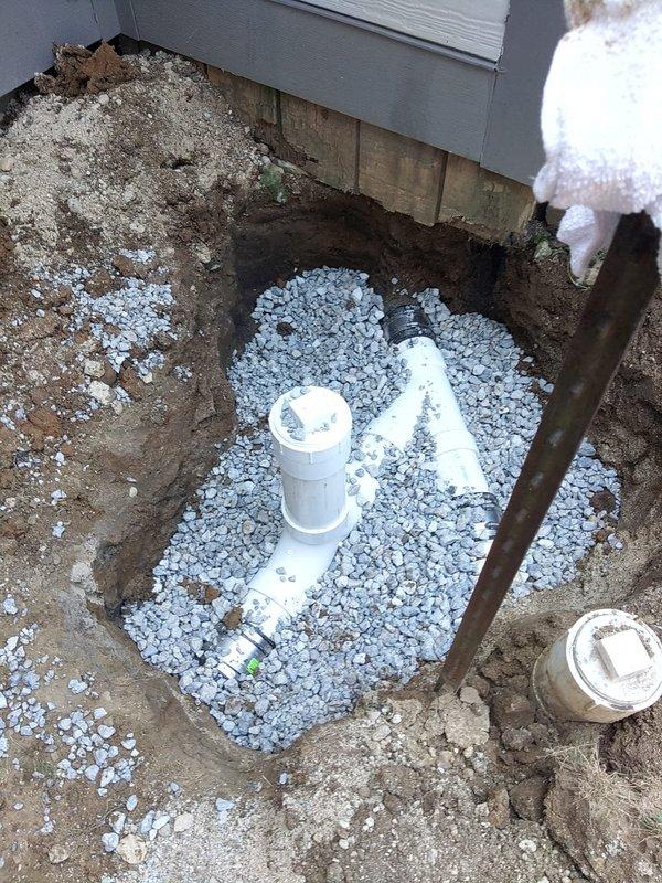 Completed main sewer line repair requiring excavation adjacent to building foundation. Exposed and replaced damaged sewer piping with new PVC pipe sections, installed within proper gravel bedding for drainage and structural support. Work included trenching, removal of failed pipe segments, installation of new connections with appropriate fittings, and backfilling with drainage rock to ensure long-term system integrity and proper water flow away from the foundation.