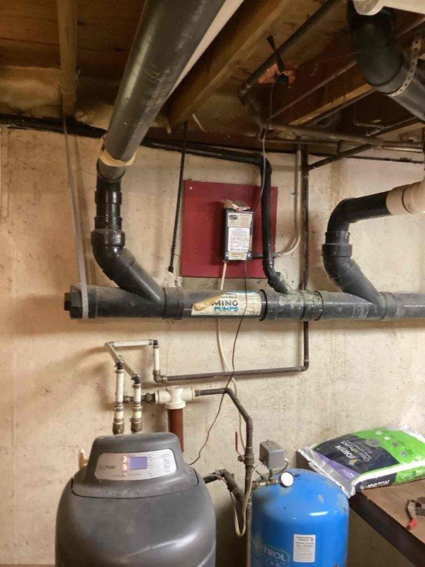 Completed installation of washing machine drain line connection to existing sewer system. Accessed exterior sewer line in wooded area behind property and tied in new drain line to accommodate laundry facility. Verified proper drainage flow and confirmed all connections in basement mechanical room where washing machine hookup is located, ensuring compliance with plumbing codes and proper venting.