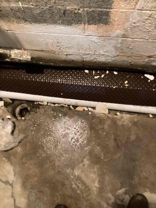 Conducted on-site assessment of exposed flood drain system in basement area requiring repair. Inspected white PVC drainage piping running horizontally through the space, along with associated heating register components and concrete surfaces showing signs of moisture exposure and deterioration. Documented existing conditions including deteriorated insulation material with significant cracking and flaking, perforated metal HVAC components with visible water staining and mineral deposits, and concrete block walls displaying efflorescence. Provided detailed photographic documentation of the flood drain system and surrounding infrastructure to prepare comprehensive repair estimate for the exposed drainage work as requested.