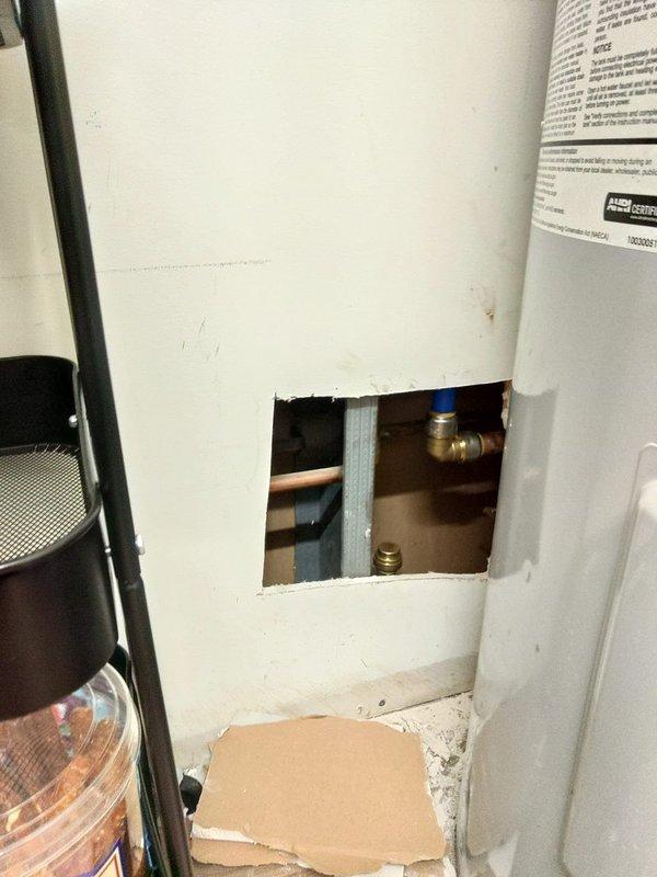 Installed water meter in commercial facility plumbing system. Created wall access opening to expose existing copper supply lines, installed brass fittings and blue-handled shutoff valve, and integrated new metering equipment into the water distribution system. All connections were secured and tested for proper operation.