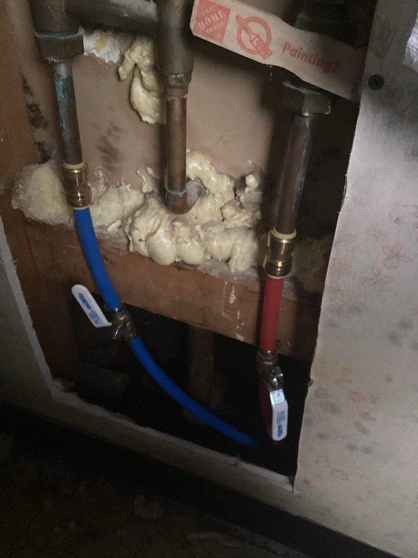Replaced damaged waterlines with new copper piping and flexible supply lines. Installed brass fittings to connect vertical copper pipes to color-coded hot and cold water supply lines, secured the plumbing assembly to wooden backing board, and applied spray foam insulation around all pipe penetrations to seal gaps and prevent air infiltration. All connections were tested for proper flow and verified leak-free operation upon completion.