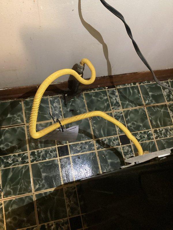 Responded to gas leak service call and performed comprehensive pressure testing of gas lines. Upon arrival, conducted thorough inspection of the affected area and utilized specialized testing equipment to identify and verify the leak location. Successfully completed pressure test protocol to ensure system integrity and safety compliance. Documentation captured showing testing apparatus in place with yellow corrugated test hose connected to gas line system for pressure monitoring and leak detection verification.