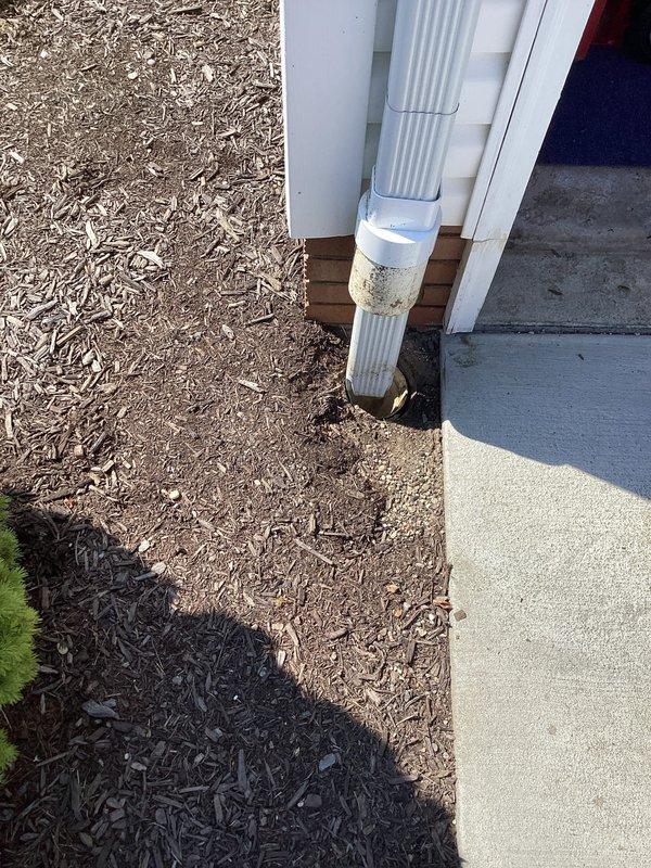 Responded to water pooling issue at garage corner caused by inadequate downspout drainage. Excavated and installed underground drainage system to redirect water away from structure foundation. Resolved erosion problem in mulch bed and eliminated moisture intrusion affecting interior garage wall.