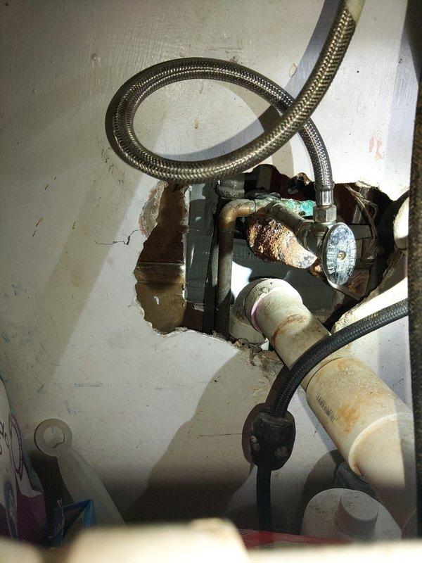 Responded to water leak complaint in older residential property. Upon inspection, identified heavily corroded valve assembly on water heater with significant rust accumulation at outlet port, indicating active moisture exposure and probable leak source. The brass/bronze valve body exhibited extensive oxidation and patina consistent with age-related deterioration. Inspected associated braided stainless steel flex lines and PVC connections for additional compromise. Documented condition of corroded components and plumbing configuration in utility space. Assessed surrounding areas including basement/crawlspace plumbing for related leak issues or water damage.