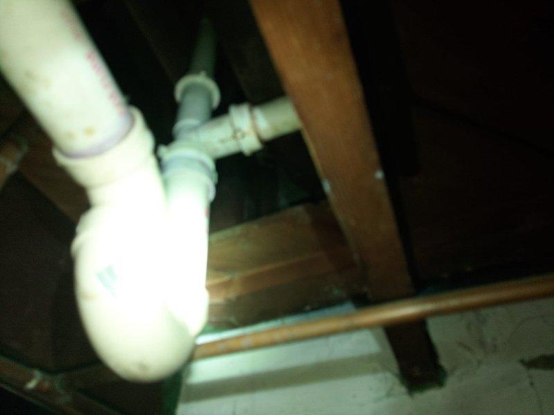 Responded to water leak complaint in older residential property. Upon inspection, identified heavily corroded valve assembly on water heater with significant rust accumulation at outlet port, indicating active moisture exposure and probable leak source. The brass/bronze valve body exhibited extensive oxidation and patina consistent with age-related deterioration. Inspected associated braided stainless steel flex lines and PVC connections for additional compromise. Documented condition of corroded components and plumbing configuration in utility space. Assessed surrounding areas including basement/crawlspace plumbing for related leak issues or water damage.