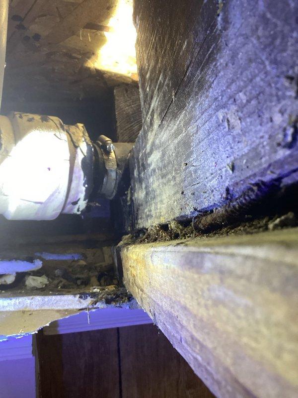 # Plumbing Service - Water Leak

Responded to a callback for an unresolved bathroom leak in an 80-year-old residence. Upon arrival, accessed the attic crawl space above the affected bathroom to investigate the source of the persistent leak. Inspection revealed compromised plumbing connections in the confined space where water supply lines interface with aged structural components.

Navigated through the tight attic access point to examine PVC piping and brass fittings located near HVAC ductwork and fiberglass insulation. Identified the leak source at a threaded pipe connection that had failed due to deterioration of the fitting and movement in the aging structure. The original repair from the previous visit had not addressed the root cause of the leak, which was related to settling and structural flex in the 80-year-old framing.

Performed necessary repairs to the compromised connection, ensuring proper sealing and support to prevent future movement-related failures. Documented the con