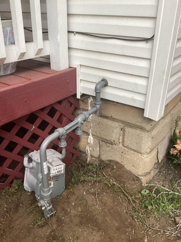 Completed monthly maintenance observation (MMO) of commercial gas meter installation. Inspected exterior gas meter mounted on foundation, verified proper piping connections, and documented current condition of meter assembly and associated infrastructure. Interior utility space was also inspected where gas line enters building through foundation wall. All components photographed for service records, with no immediate repairs or adjustments required at this time.