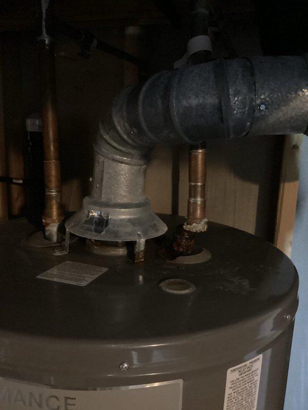 Responded to emergency service call for failed tanked water heater with rupture at top of unit causing flooding in utility area. Upon arrival, found approximately two inches of standing water on floor and complete loss of water supply to property. Assessed water heater showing significant age-related deterioration, including corroded copper piping connections and compromised tank integrity at upper dome section. Documented existing conditions including deteriorated plumbing connections, water meter assembly with visible corrosion and biological growth, and water damage to surrounding concrete surfaces. Coordinated scheduling to accommodate time constraints while ensuring prompt response to restore water service to residence.
