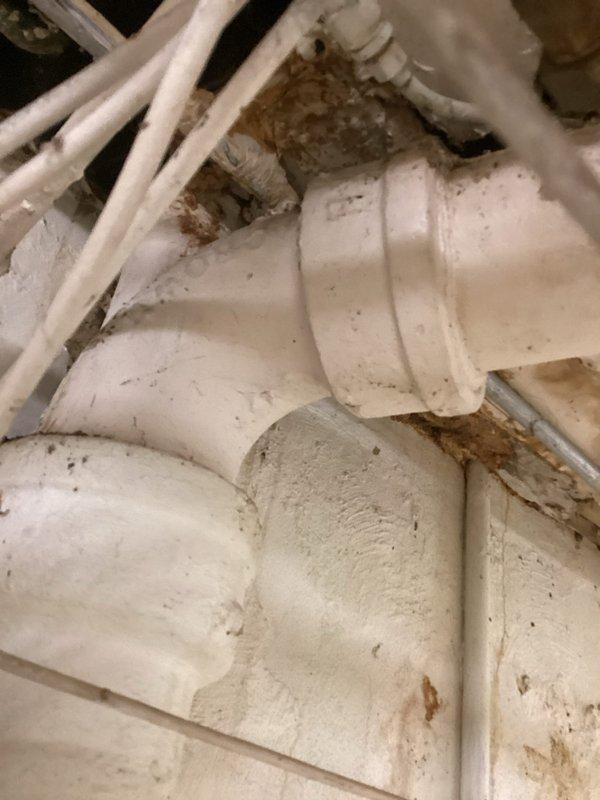 Responded to emergency call for leaking pipe in basement of 99-year-old residential property. Upon arrival, conducted thorough inspection of plumbing system and identified active water leak at deteriorated pipe section in ceiling cavity. Assessment revealed extensive water damage to surrounding drywall and structural materials, with visible discoloration, material separation, and potential mold growth indicating prolonged moisture intrusion. 

Located source of leak at corroded section of supply line showing significant sediment buildup and surface deterioration consistent with age of home's original plumbing infrastructure. Isolated affected water line and performed emergency repair to stop active leak. Evaluated condition of adjacent PVC piping running through ceiling joists, noting accumulation of dirt, dust, and brown staining at pipe intersections. 

Documented all damage with photographs showing extent of deterioration at wall-ceiling junction and condition of exposed plumbing li