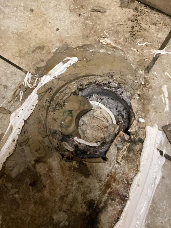 Responded to complaint of raw sewage odor in men's restroom. Upon inspection, discovered significant buildup and contamination around toilet base and floor drain. Toilet exhibited staining and discoloration at floor connection point, indicating potential wax ring failure or seal compromise allowing sewer gases to escape. Floor drain showed heavy sediment accumulation, debris blockage, and signs of dried efflorescence suggesting chronic moisture issues and possible trap seal evaporation. Cleared drain obstruction, flushed system to restore proper trap seal, and sanitized affected areas. Recommended monitoring for recurring odors and consideration of trap primer installation to prevent future dry trap conditions.