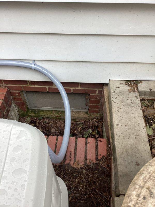 Responded to service call for natural gas line installation to generator. Located existing gas supply line in basement/crawl space area with shut-off valve on galvanized pipe system. Tapped into main gas line and extended new gas piping from basement location to exterior generator unit positioned near foundation. Routed gas line through foundation to reach standby generator equipment located outside on brick paver surface adjacent to cream-colored vinyl siding. Installed appropriate fittings and connections to ensure proper gas supply to generator. Verified all connections were secure and system was ready for pressure testing and final inspection.