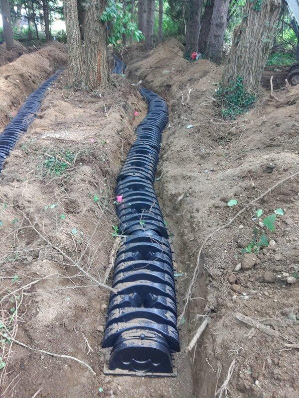 Completed installation of new septic drainage system in wooded residential area, excavating two parallel trenches and installing black corrugated drainage pipes for proper waste water dispersion. Coordinated site access with on-site occupant and worked alongside electrical contractor to ensure proper system integration and functionality.