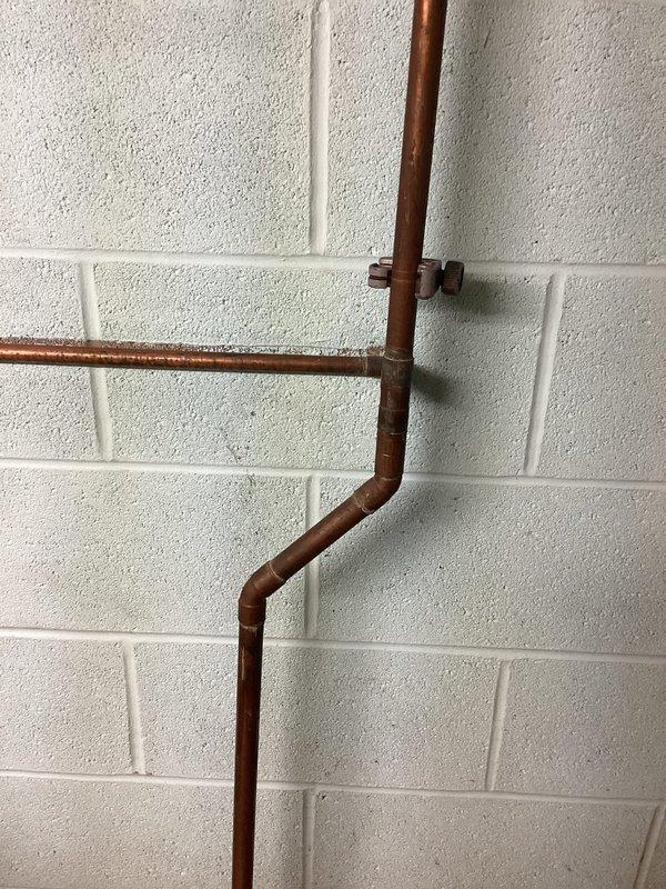 Responded to copper pipe leak in building's plumbing system. Located and assessed the leak point in the copper piping configuration mounted against the interior cinder block wall. Repaired the compromised copper pipe section by addressing the failed solder joint, ensuring proper water-tight seal and restoring full system integrity. Verified all connections and tested the system to confirm no additional leaks were present.