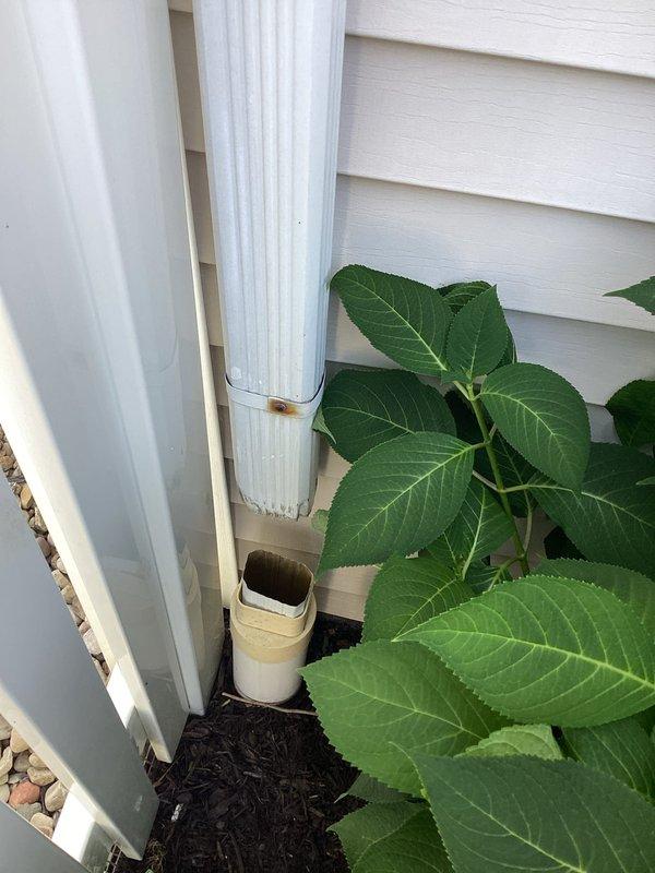 Replaced missing one-foot section of white vertical downspout on right side of building exterior. The downspout system was restored to proper functionality, ensuring effective drainage from the roof to ground level and preventing water damage to the building foundation and landscaping.